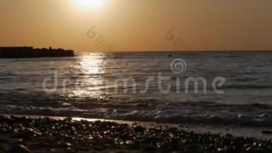 黎明<strong>时</strong>太阳从海面升起. 清晨的阳光下，海浪和鹅卵石。